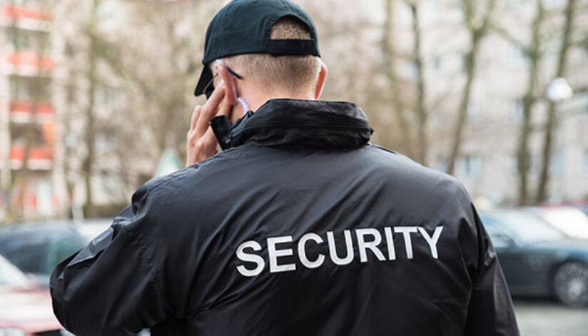 A security guard patrolling outdoors while communicating through ear piece to the team.