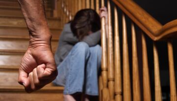 A clutched fist of a parent in front of a child siting on stairs.