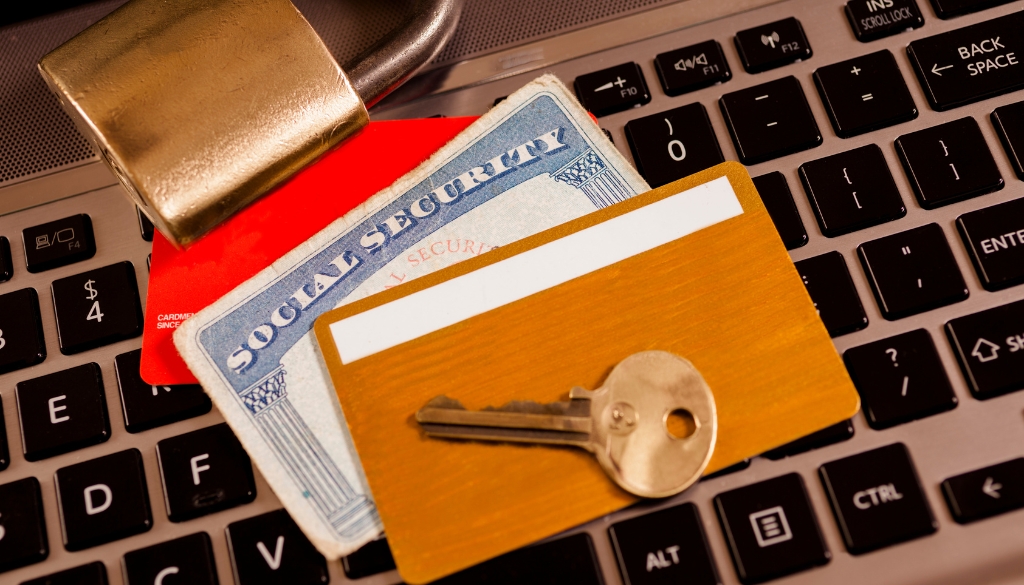 A small pile of various items, that are typical in Identity Theft, on top of a laptop keyboard.