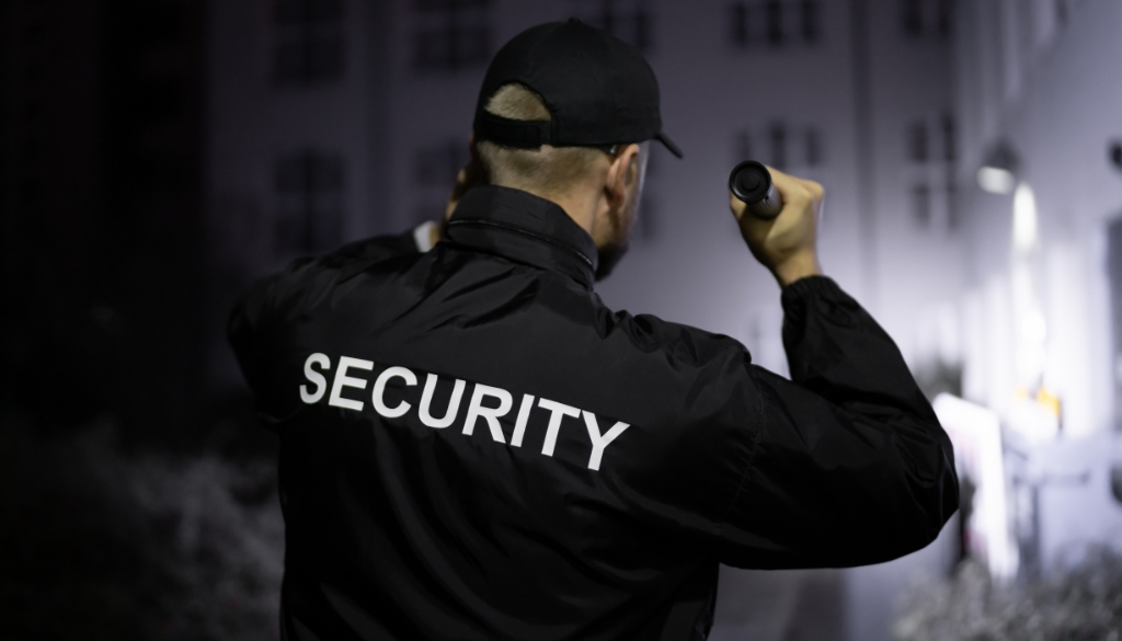 Does Your Business Need a Security Guard? Security guard patrolling an office building after hours with his flashlight.