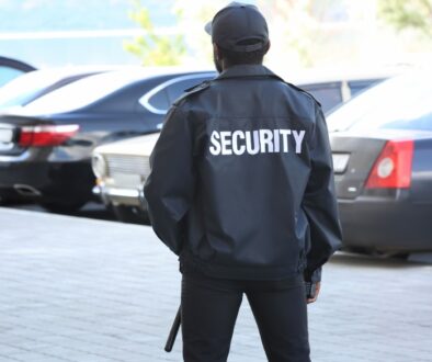 A security guard stands watch in a parking lot. O'Brien & Associates - Ensuring Business Safety and Mobile Security Excellence.