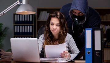 Masked man stands behind woman on computer. Empower your safety tips.
