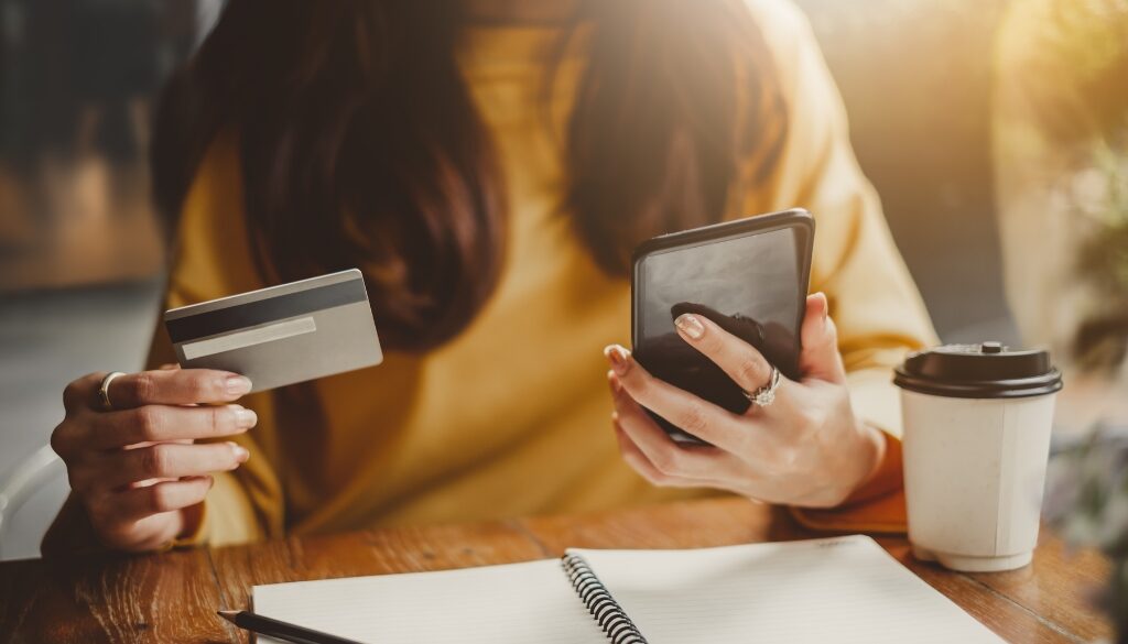 Woman holding a credit card placing an online shopping order.