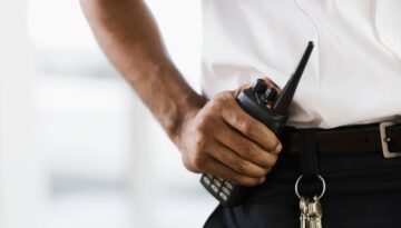 Contract security guard holding a walkie talkie.