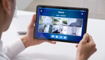 Man looking at home security camera footage on a tablet.