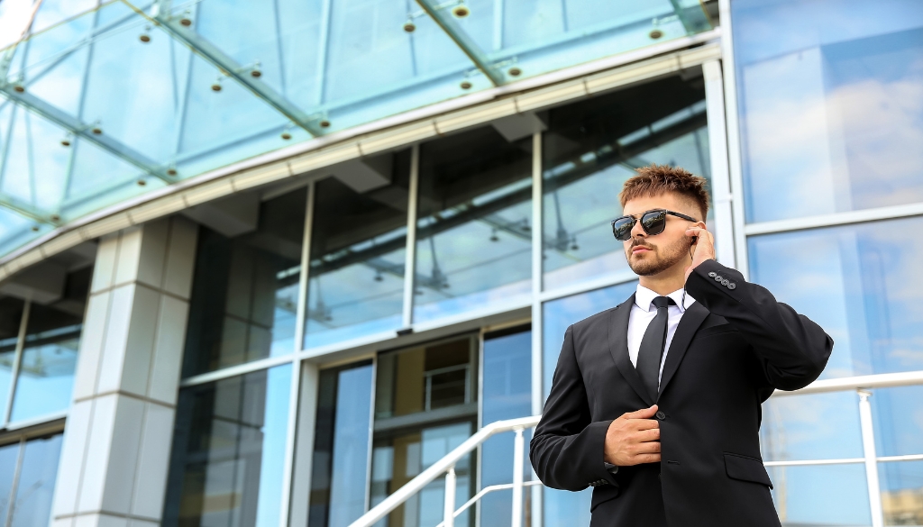 Protecting Government Buildings: Essential Security Measures For Summer Security guard standing outside of a government building listening to an earpiece.