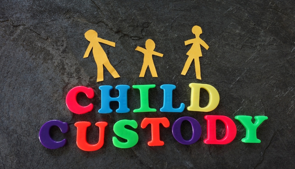 Paper cut-out people and letter magnets representing child custody and school year themes.