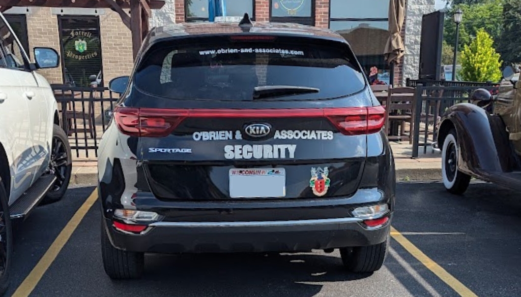 O'Brien & Associates black Kia mobile security car parked.