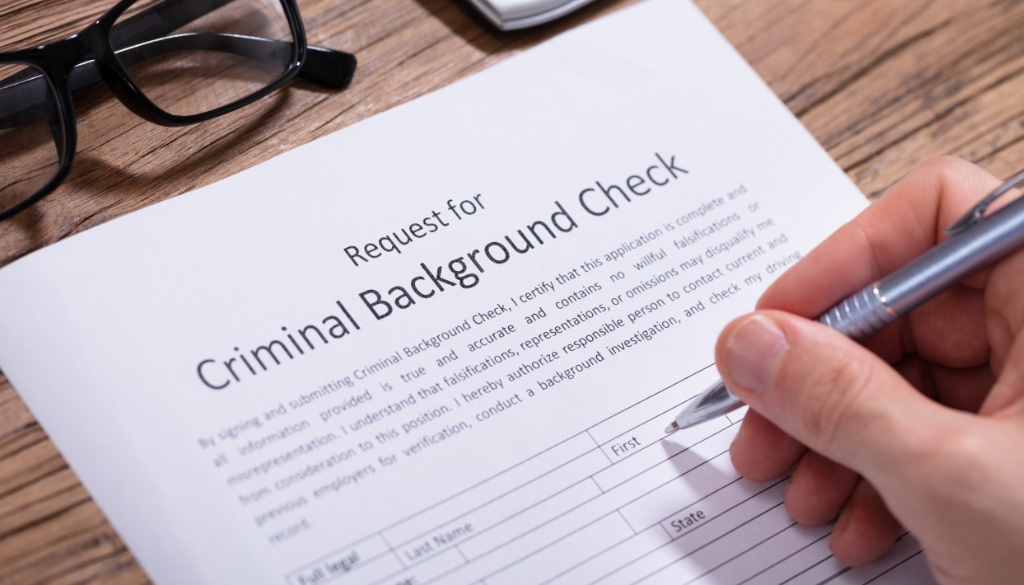 The Role Of Private Investigators In Background Checks: Ensuring Trust In New Hires A person filling out paperwork for a criminal background check.