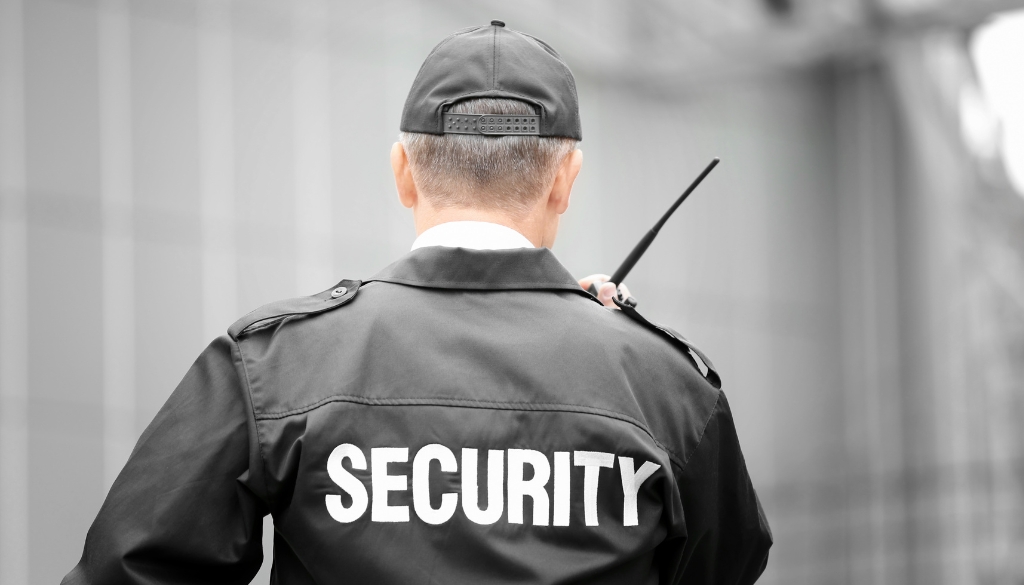 A security guard talks into a handheld transceiver radio (walkie talkie).