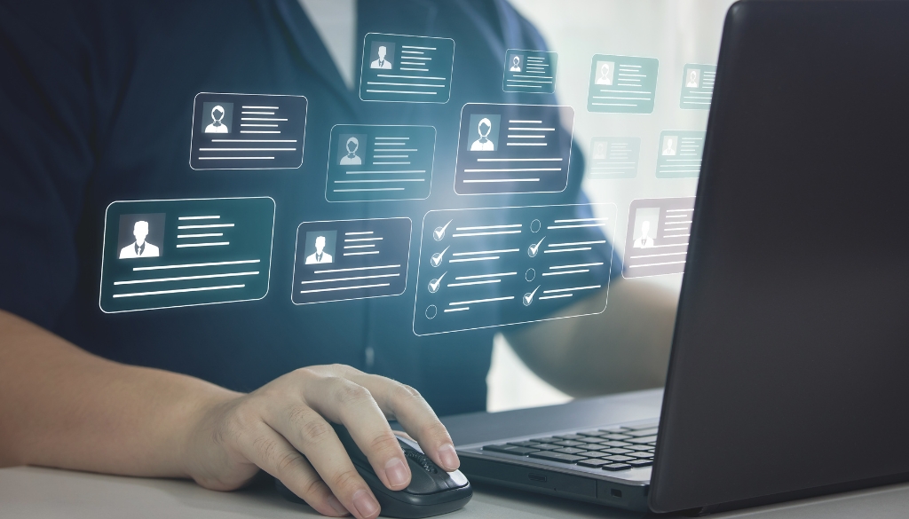 A person using a laptop with virtual icons of user profiles and checklists floating above the screen.