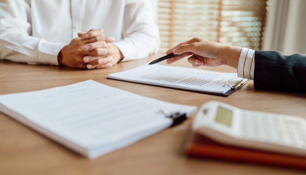 A hiring manager meeting with a prospective employee discussing details of a contract.