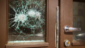 Front doors of a building with shattered glass.