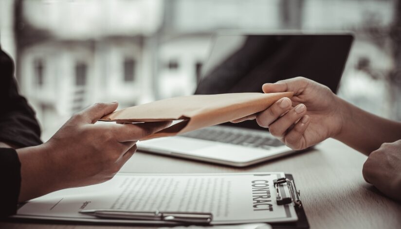 A private investigator handing a case file to a client, a contract is on the table below them.