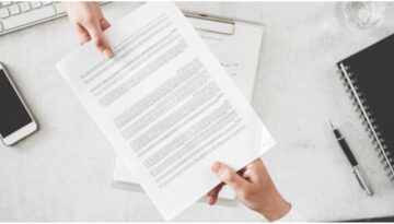Two hands hold a document on either end.