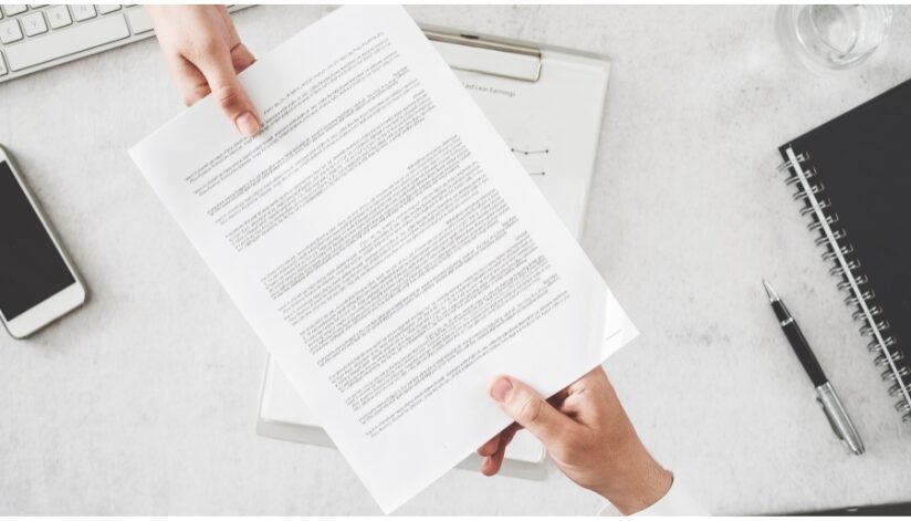 Two hands hold a document on either end.