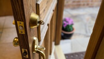 Wooden door that is ajar with a key in the deadbolt