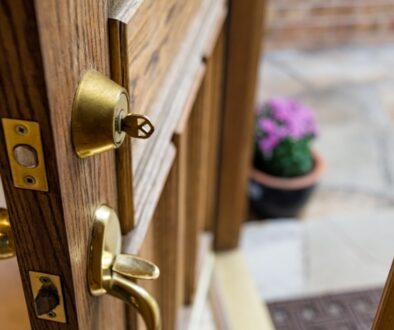 Wooden door that is ajar with a key in the deadbolt