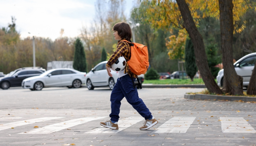 Young boy following back to school safety tips and walking to school.