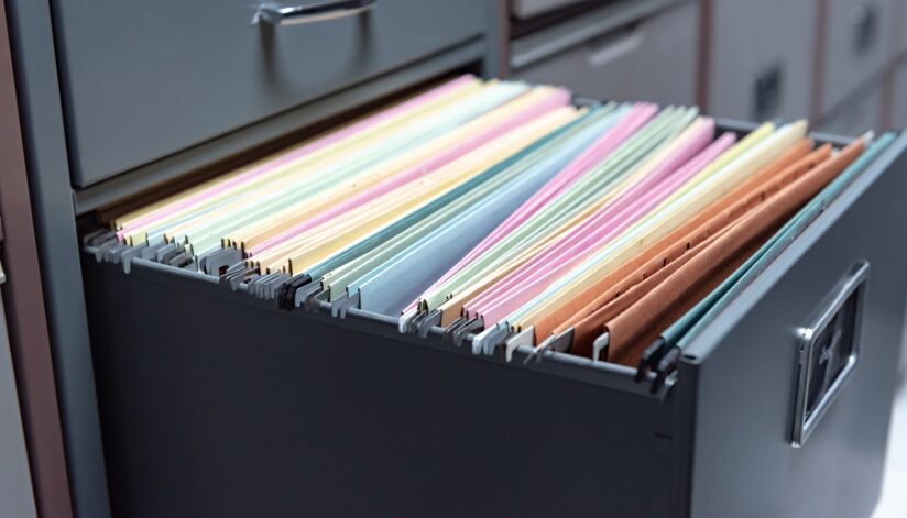 A black filing cabinet drawer opened to organized business documentation.