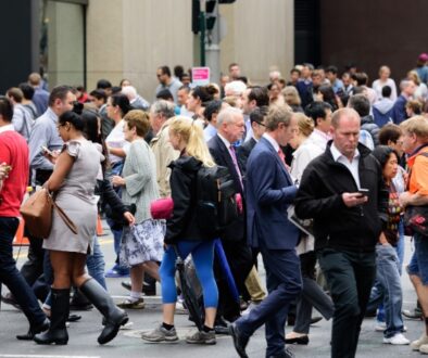 Crowd of people walking in multiple directions while looking down at their phones.