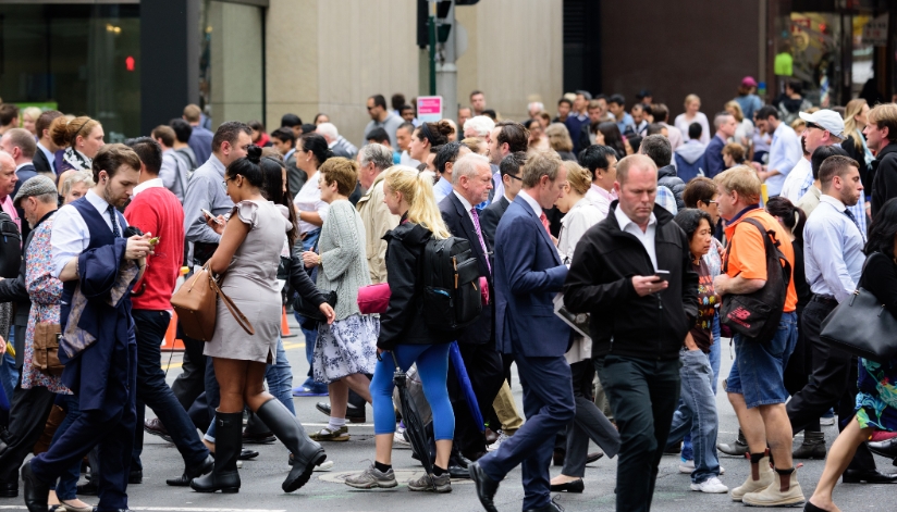 Crowd of people walking in multiple directions while looking down at their phones.