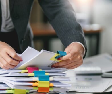 Investigator going through government investigation case files, seperated by colorful binder clips.