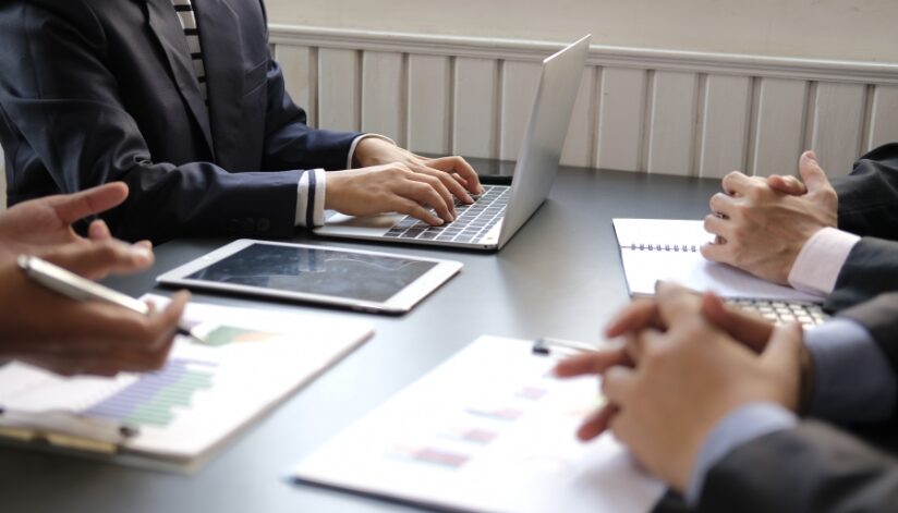 Business employees gather around a table and do their due diligence before making a business decision.